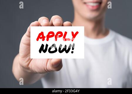 APPLY NOW! message on the card shown by a man Stock Photo