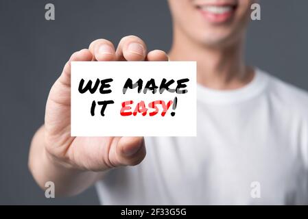WE MAKE IT EASY! message on the card shown by a man Stock Photo
