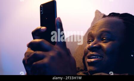 Man relaxing in the couch and browsing dating site on his smartphone. High quality photo Stock Photo