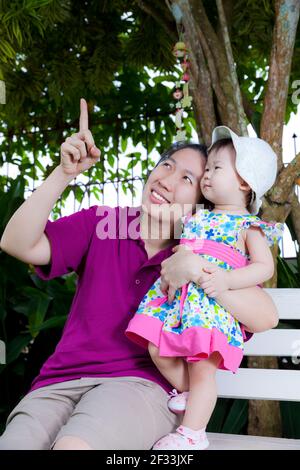 Young asian woman and cute little daughter happily in the backyard,mother pointing up Stock Photo