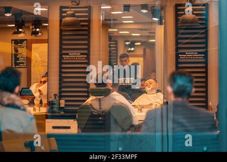 18.12.2019, Istanbul, Turkey. Barbershop. A man is sitting in a chair, waiting for the shaving procedure. View of the interior through the glass windo Stock Photo