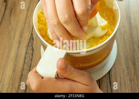 Hand squeezing oranges fresh on the orange press with pulp Stock Photo