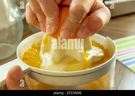 Hand squeezing oranges fresh on the orange press with pulp Stock Photo