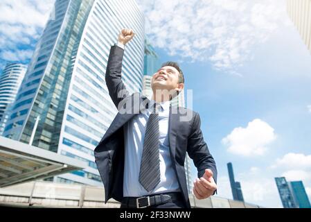 Businessman smiling and raising his fist in the air in office building ...