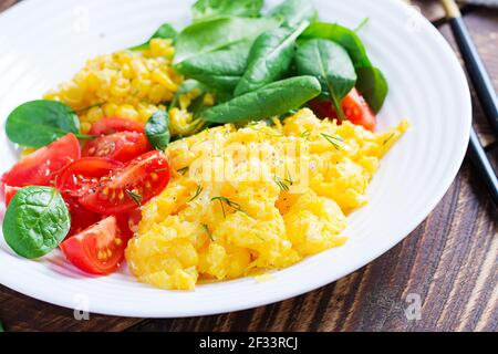 Breakfast. Scrambled eggs with cherry tomatoes, spinach  and corn. Stock Photo