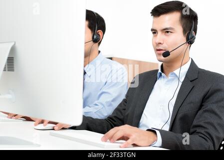 Businessmen wearing microphone headset in call center as the operators, telemarketers or customer service staffs etc. Stock Photo