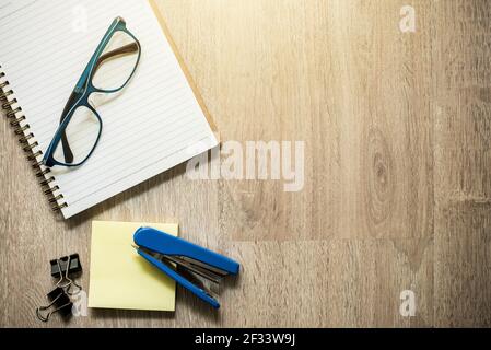 Notebook, eyeglasses  and some stationery supplies on wood background, top view (flat lay) with copy space Stock Photo