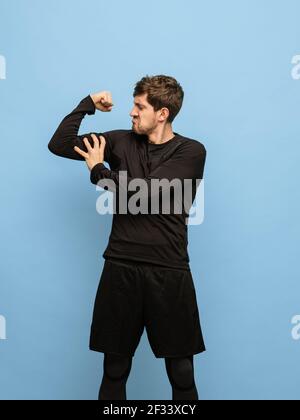 Portrait of athletic Caucasian man in black attire isolated on blue background. Stock Photo