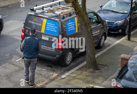 The vehicle of a electric service company and the electrician on call out to carry out electrical work. Stock Photo