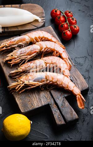Set of king shrimps with ingredients for paella on black concrete surface, food photo. Stock Photo