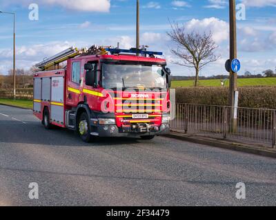 A red Scania fire engine on an urban road in the UK, taken in winter. Stock Photo