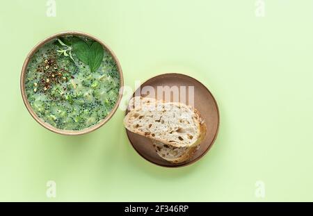 Fresh broccoli cream soup served fresh bread and spices in craft container. Vegetarian lunch to go. Stock Photo