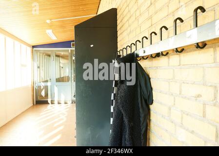 coat rack in a school hall with jacket hanging on it Stock Photo