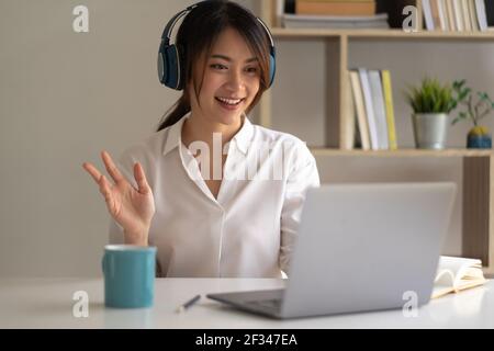 Beautiful asian woman in headphones have video call distant class with teacher using laptop - Online learning concept. Stock Photo