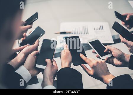 group of employees using their smartphones in the workplace Stock Photo