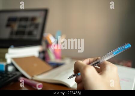 Creative thinking concept. A pen in a hand with messy working table in the background. Stock Photo
