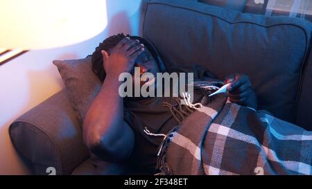 Sick african american man turning on the couch. High fever, illness covid-19. High quality photo Stock Photo