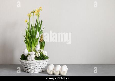 Easter handmade flower composition with blossom narcissus and hyacinth flowers and organic eggs in white wicker basket. Spring flowering bulbs in a po Stock Photo