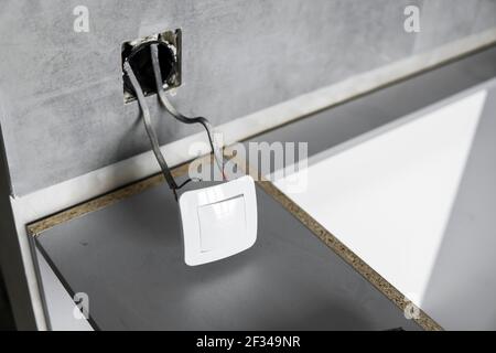 Repair or installation of a new light switch in the wall. Light switch connected via cables to a electricity in a home. Stock Photo