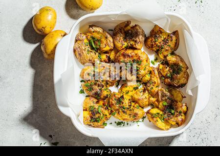 Baked smashed potatoes with herbs in oven dish. Stock Photo