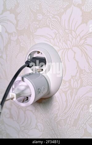 white wall socket with two cables plugged in Stock Photo
