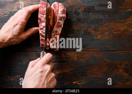 beef marbled steak. Chuck eye roll on the cutting Board. Organic beef. with butcher hands and meat cleaver at work chop. Space for text. Stock Photo