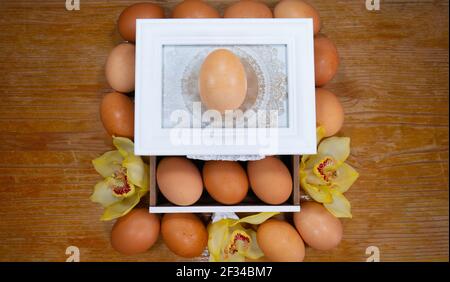 Congratulatory Easter background. Chicken eggs, wooden box and yellow  orchids flowers. Stock Photo