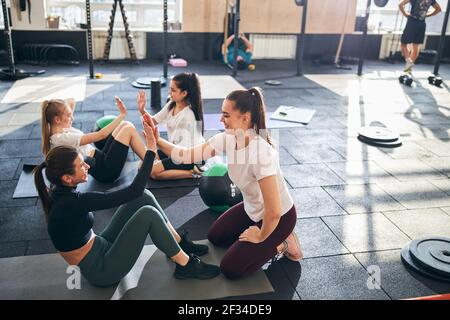 Positive ladies doing abs workout at the gym Stock Photo