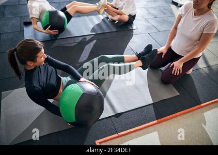 Focused young ladies performing abs exercises at gym Stock Photo