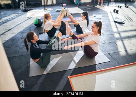 Positive female gymnasts exercising in pairs at gym Stock Photo