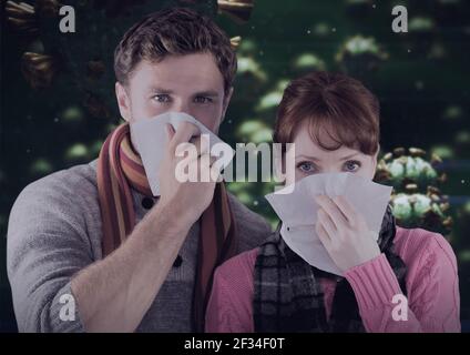 Composition of covid 19 cells over sick man and woman blowing their noses Stock Photo