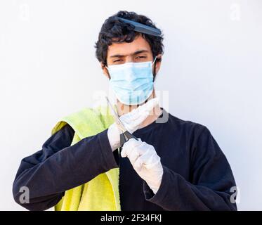 Arabic Muslim guy wearing mask and holding barber equipment Stock Photo