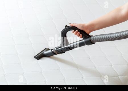 Professional cleaning mattress by vacuum cleaner from dust bacteria dirty. Female hand use vacuum cleaner machine for cleaning mattress in apartment. Stock Photo