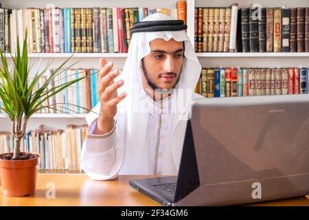 Arabic muslim man using his laptop to do seminars online Stock Photo
