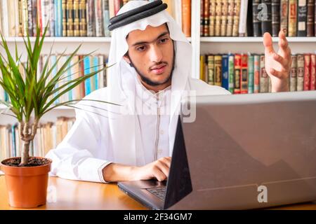 Arabic muslim man using his laptop to do seminars online Stock Photo