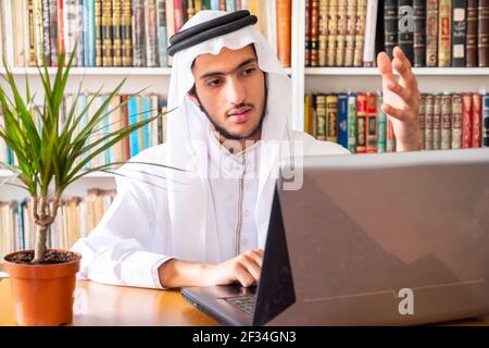 Arabic muslim man using his laptop to do seminars online Stock Photo