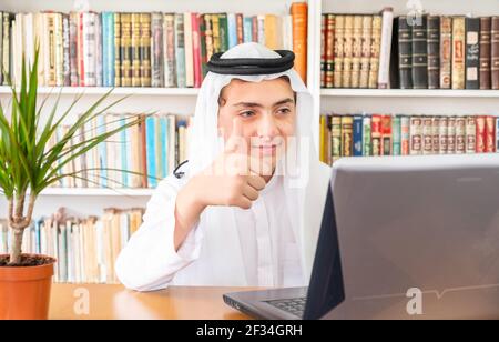 Arabic muslim man feeling happy and giving thumbs up online Stock Photo