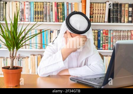 Arabic muslim man feeling bored at his home office Stock Photo