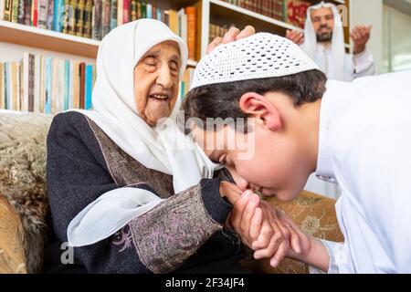 Arabic Muslim son kissing his grandmother hand Stock Photo