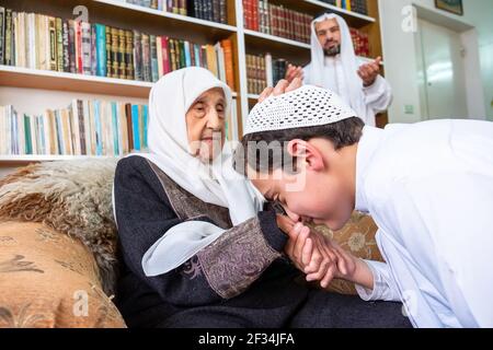 Arabic Muslim son kissing his grandmother hand Stock Photo