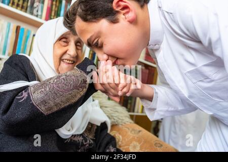 Arabic Muslim son kissing his grandmother hand Stock Photo