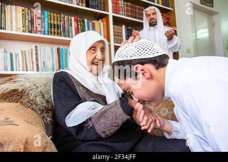 Arabic Muslim son kissing his grandmother hand Stock Photo