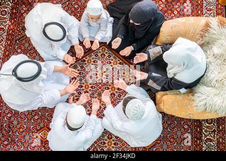 Happy Arabic family praying for god during Ramadan Stock Photo