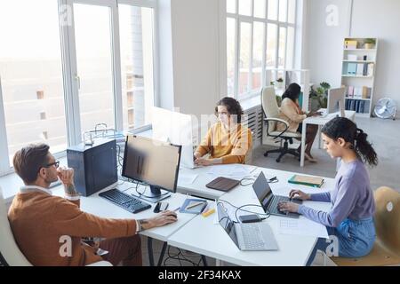 High angle view at diverse software development team using computers at workplace in white office interior, copy space Stock Photo