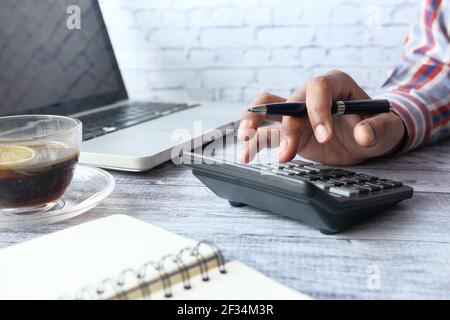 man hand using calculator and laptop on office desk Stock Photo