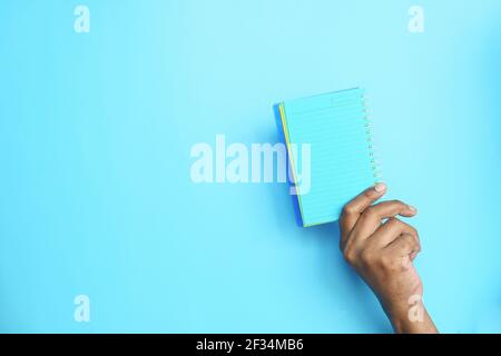 holding open notepad on blue background  Stock Photo