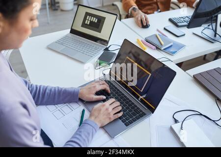 Close up of female IT programmer writing code on laptop screen while collaborating on project with team of software developers, copy space Stock Photo