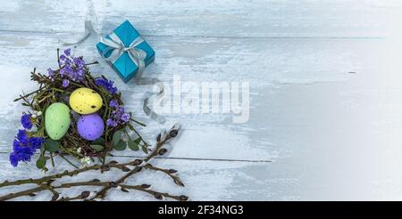 A nest with Easter eggs. Blue gift box on a gray background. Easter eggs in the nest and a gift. Stock Photo