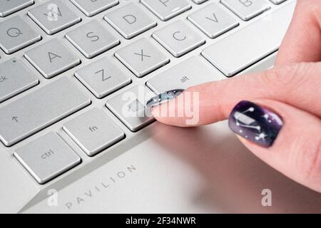 Sankt-petersburg, Russia, March 9, 2021: Laptop user finger pressing Windows icon key button on Microsoft Windows keyboard. Woman hand pressing Micros Stock Photo