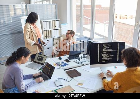 High angle view at multi-ethnic software development team using computers and writing code while collaborating on project in modern office, copy space Stock Photo